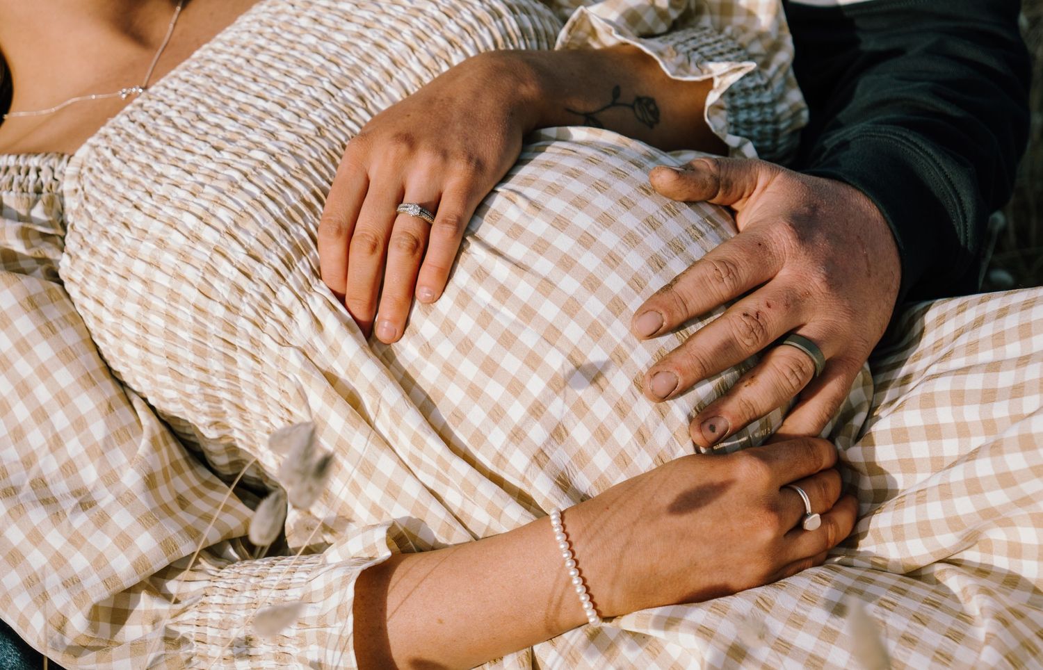 A series of hands resting on a white and beige gingham patterned fabric or bedding.