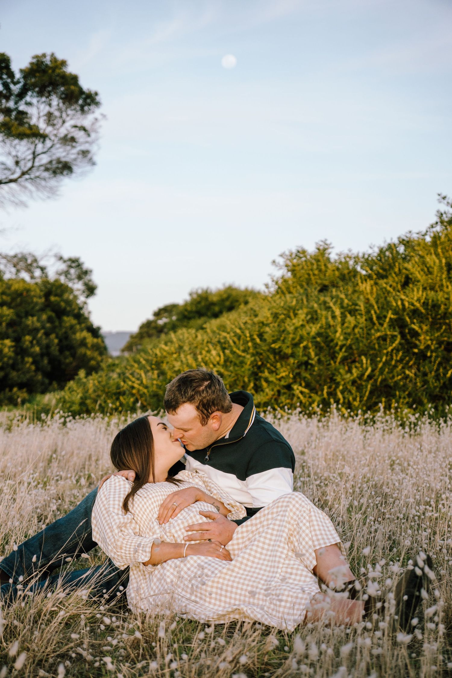 A romantic couple embraces in a field of lavender flowers during sunset.