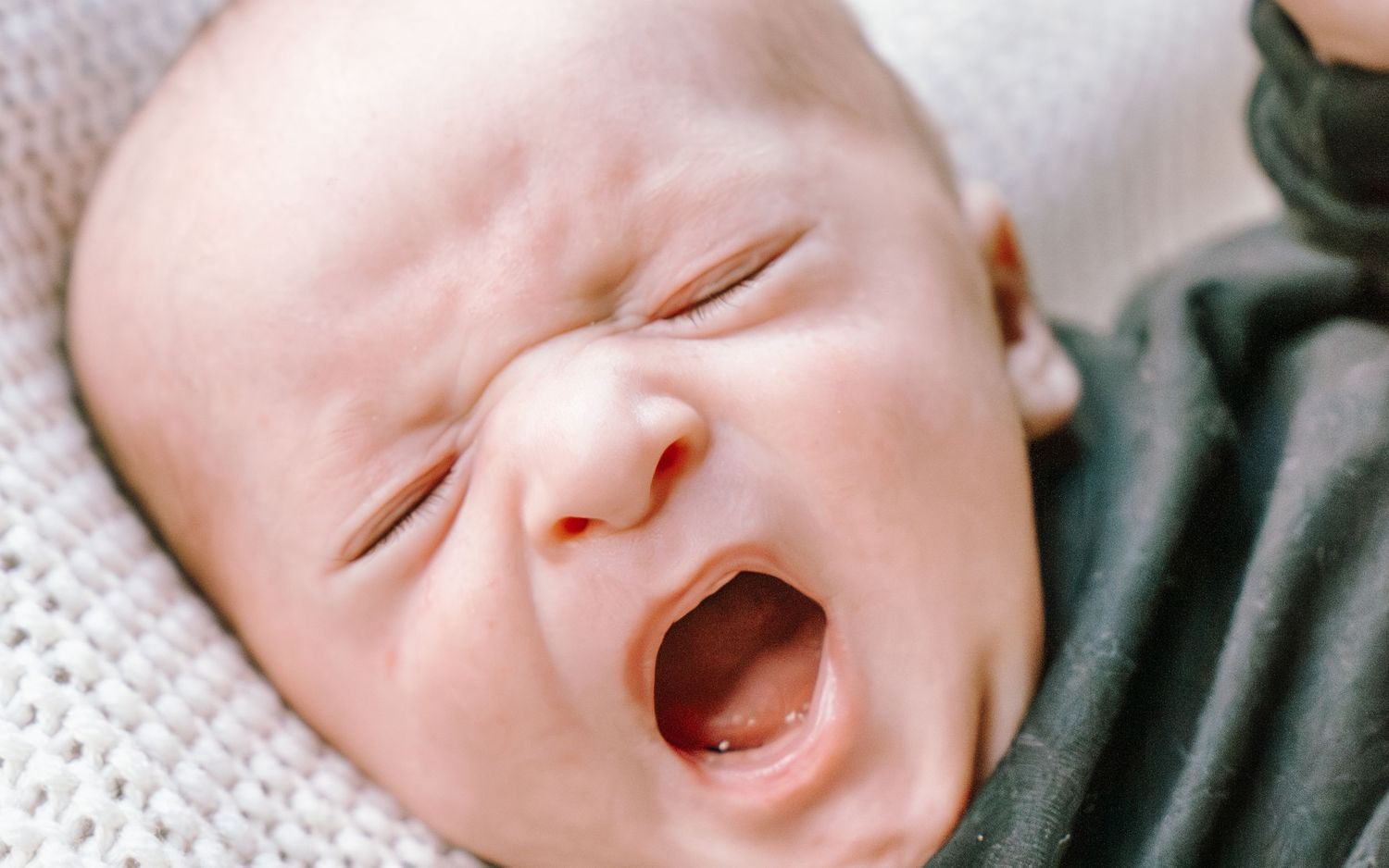 A collage of five photos showing a laughing baby in various expressions on a white blanket.