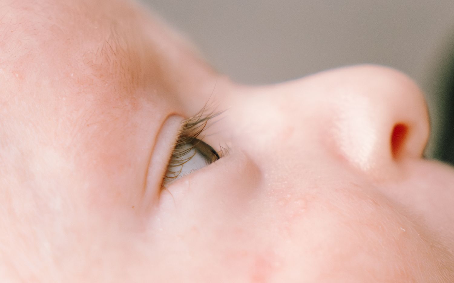 Extreme close-up macro photograph showing the eye and nose area of a face with soft, pale skin.