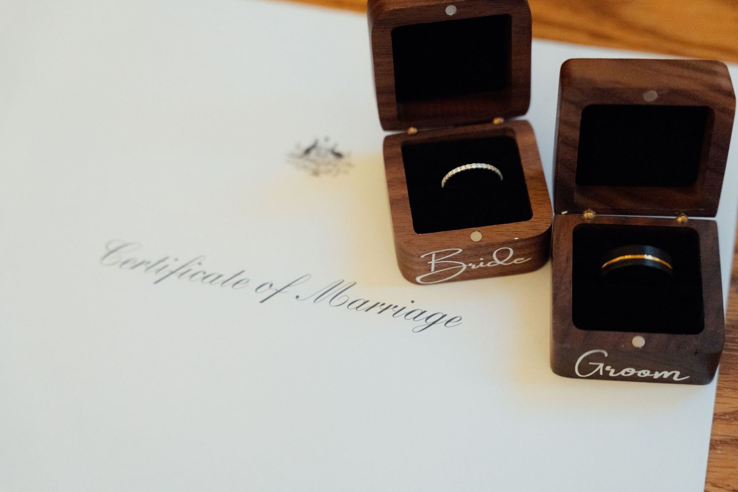 Wedding rings in wooden Bride and Groom boxes beside a Certificate of Marriage document.