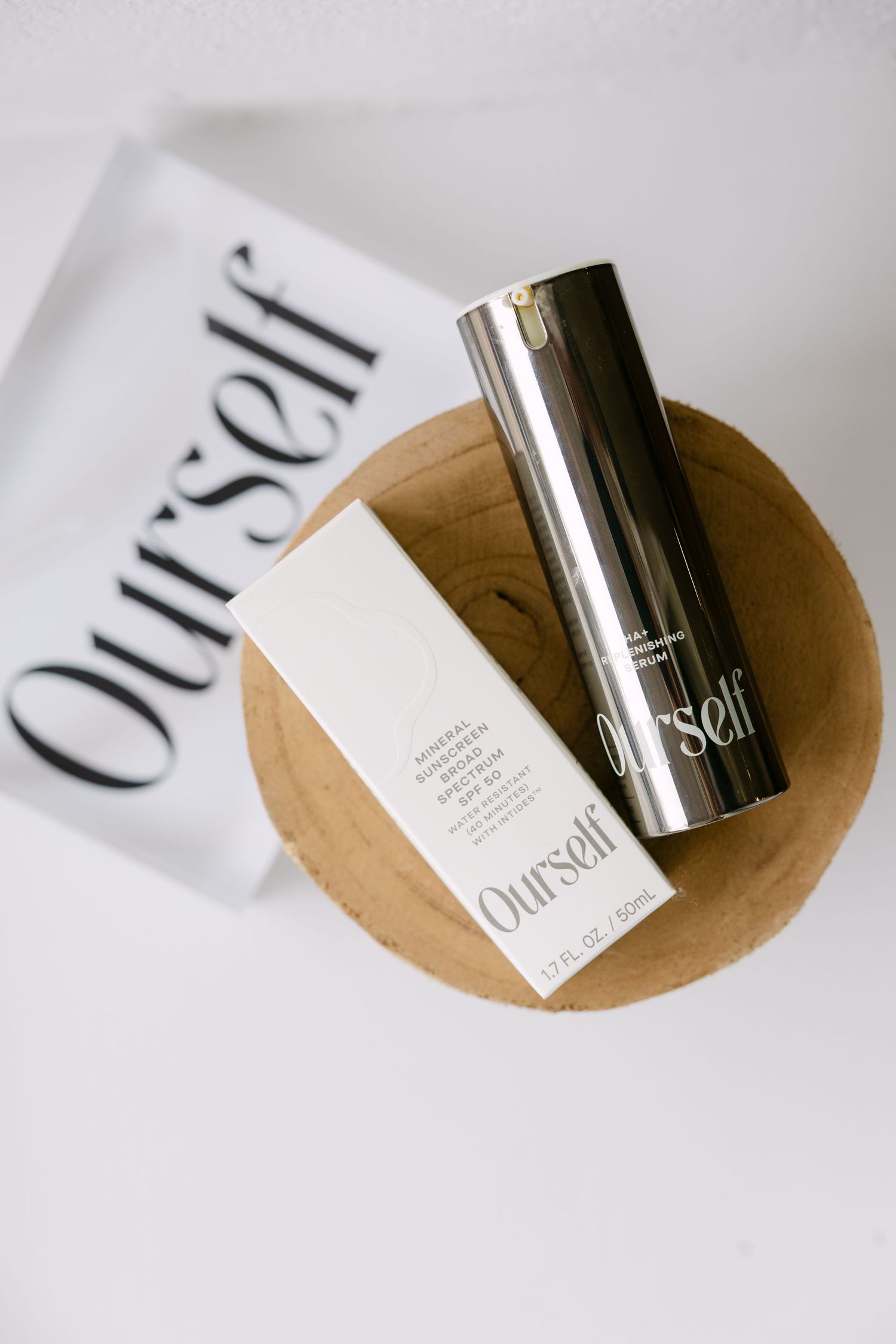 Ourself mineral sunscreen SPF 50 product displayed on wooden bowl with branded packaging.