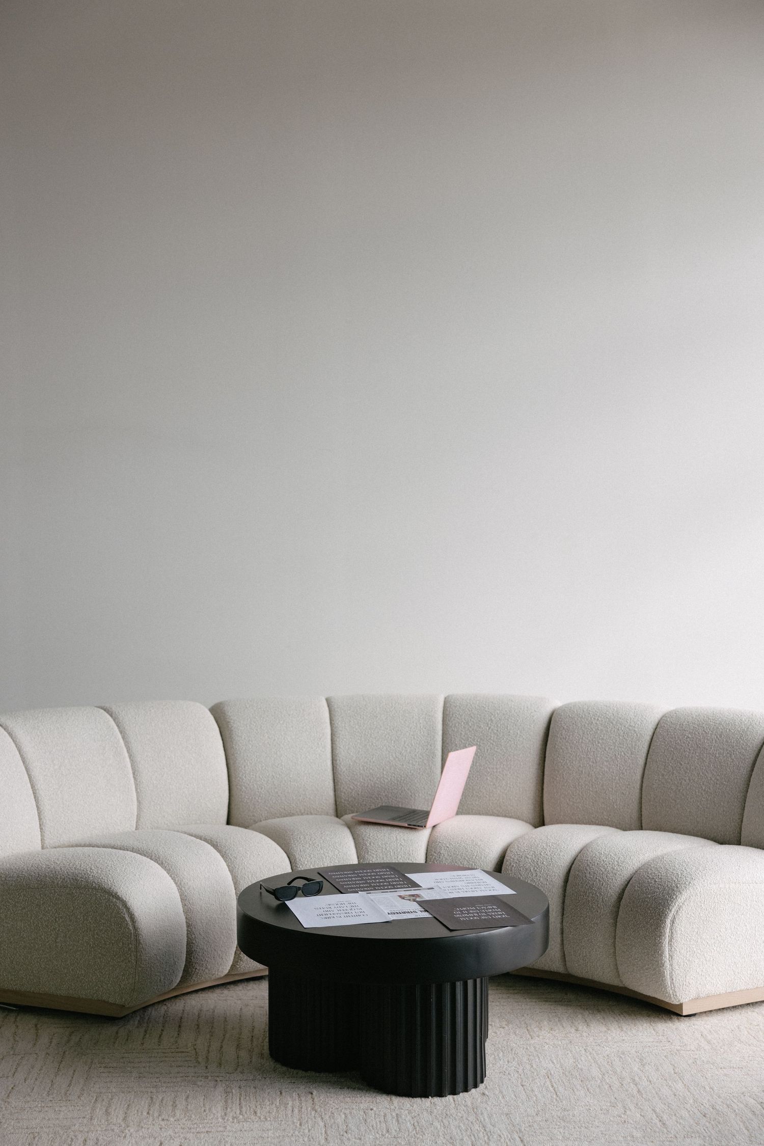 Modern minimalist living room with curved white sectional sofa and black round coffee table.