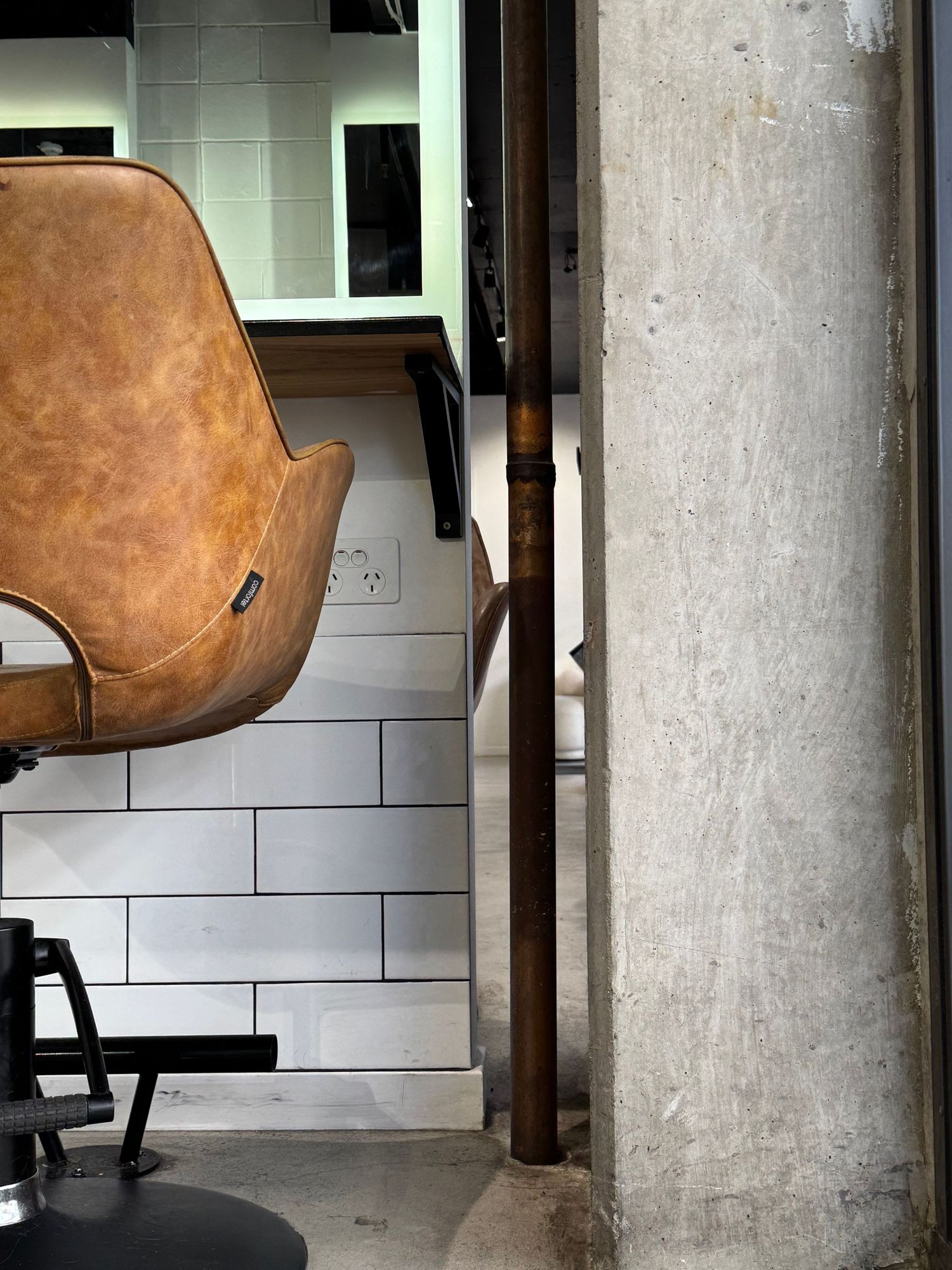 inside a hair salon cutting area. a close up of detail of a chair, wall and tiles. industrial