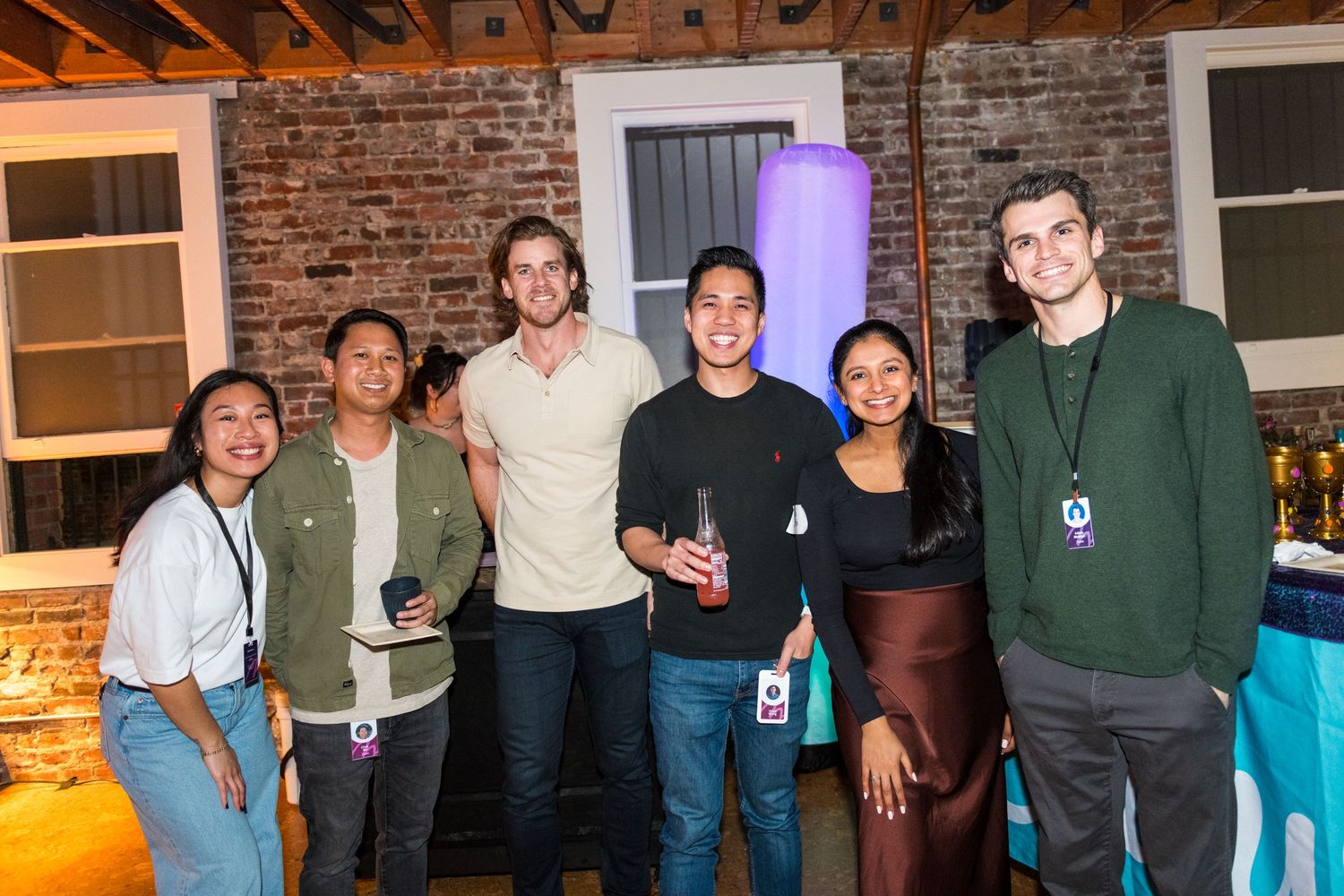 A group of people standing together in a rustic room with exposed brick walls and wooden beams.