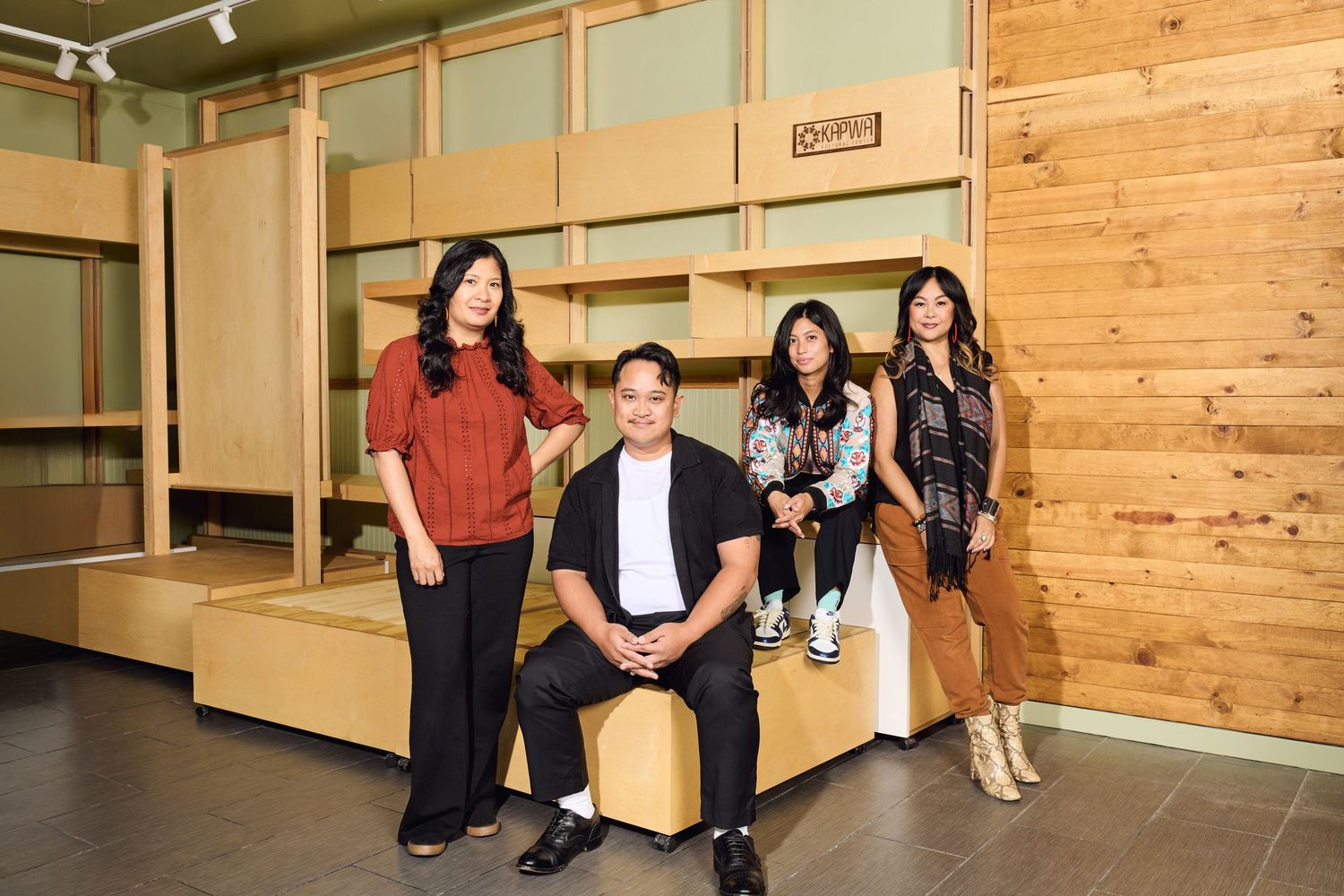 Team members seated casually in an office space with wooden wall panels and modern furnishings.