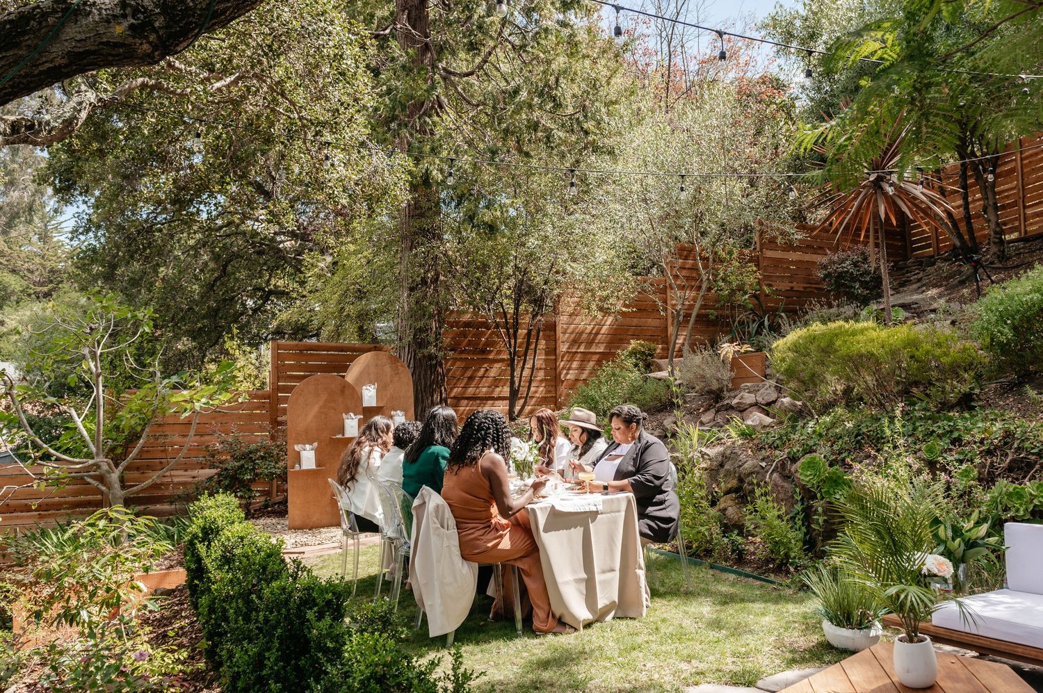 Outdoor wedding reception area decorated with rustic furniture and natural greenery.