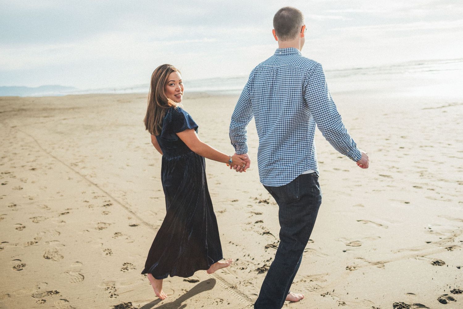 Two people walk together along a sandy beach during sunset.