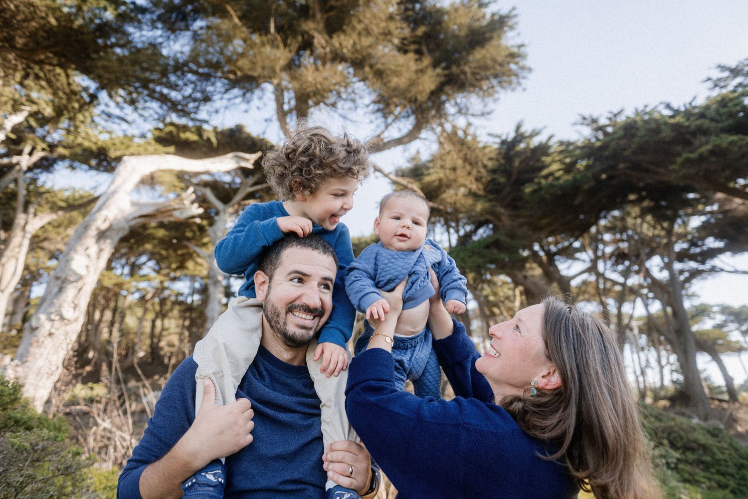 Family sharing joyful moments together in a coastal forest setting.