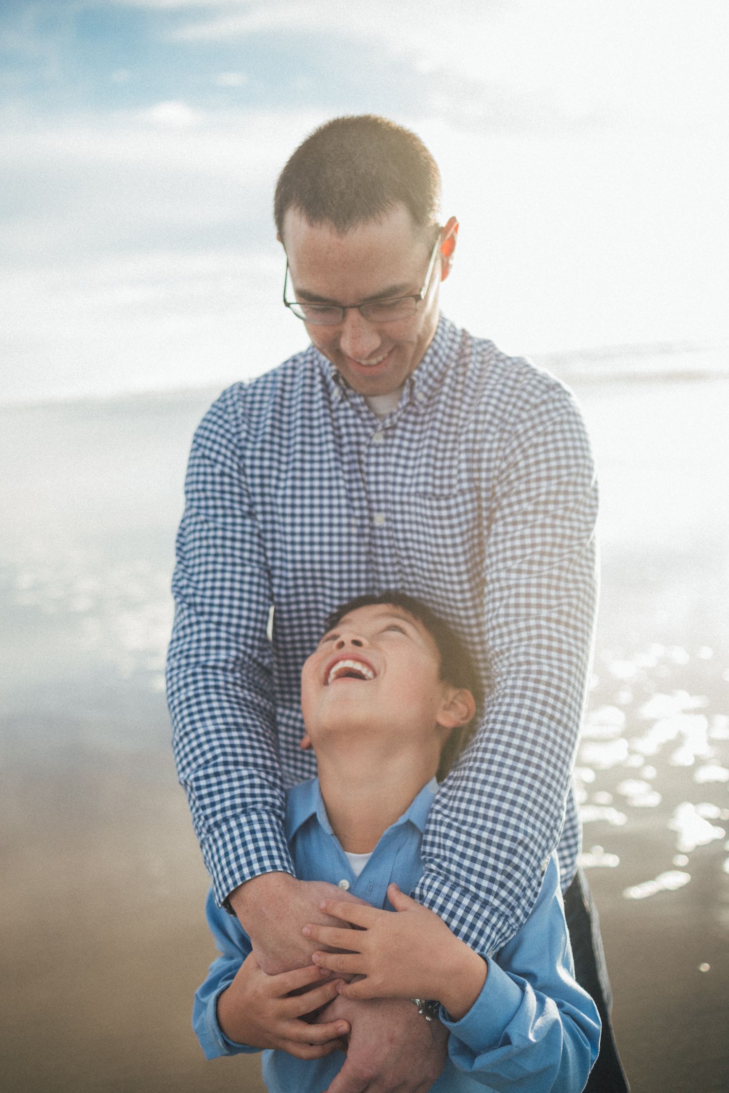 A tender moment captured between two people during a beach photoshoot at sunset.