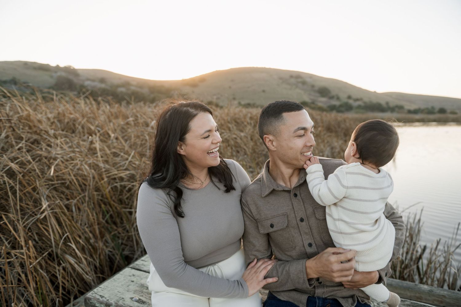Family enjoying a tender moment together against a coastal sunset backdrop.