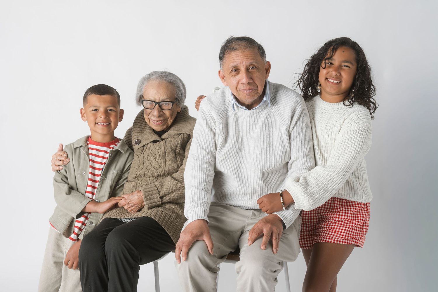 Two grandparents pose with their grandchildren in a warm family portrait against a white background.