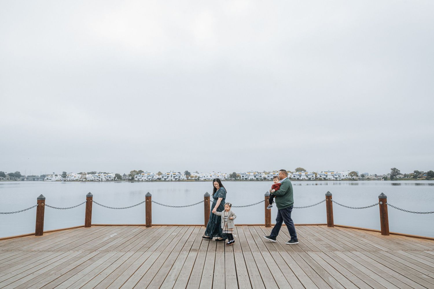 People walking along a wooden boardwalk with waterfront views.