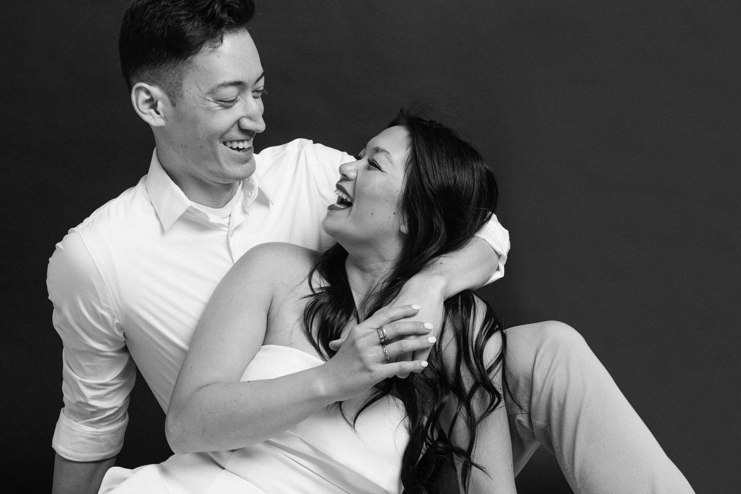 Black and white portrait of a joyful couple sharing a candid laughing moment together.
