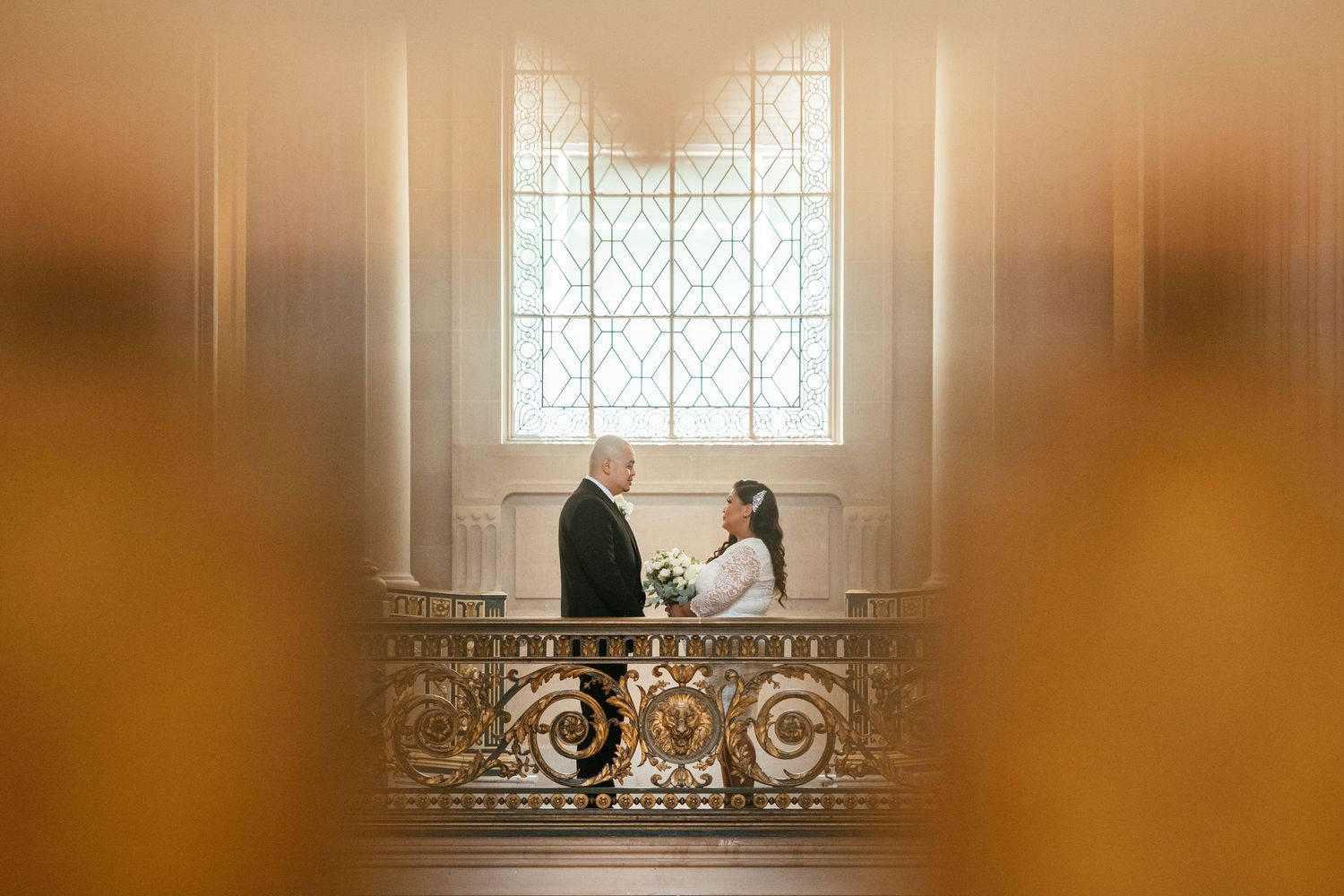 A couple sits together in a sunlit church window creating a romantic silhouette against stained glass.