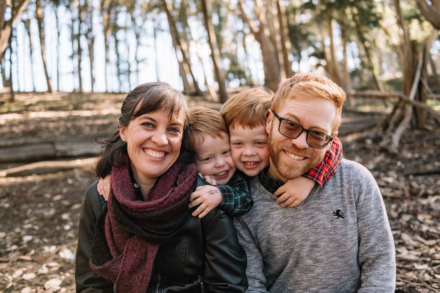 Family group hugging and laughing together during an outdoor portrait session.