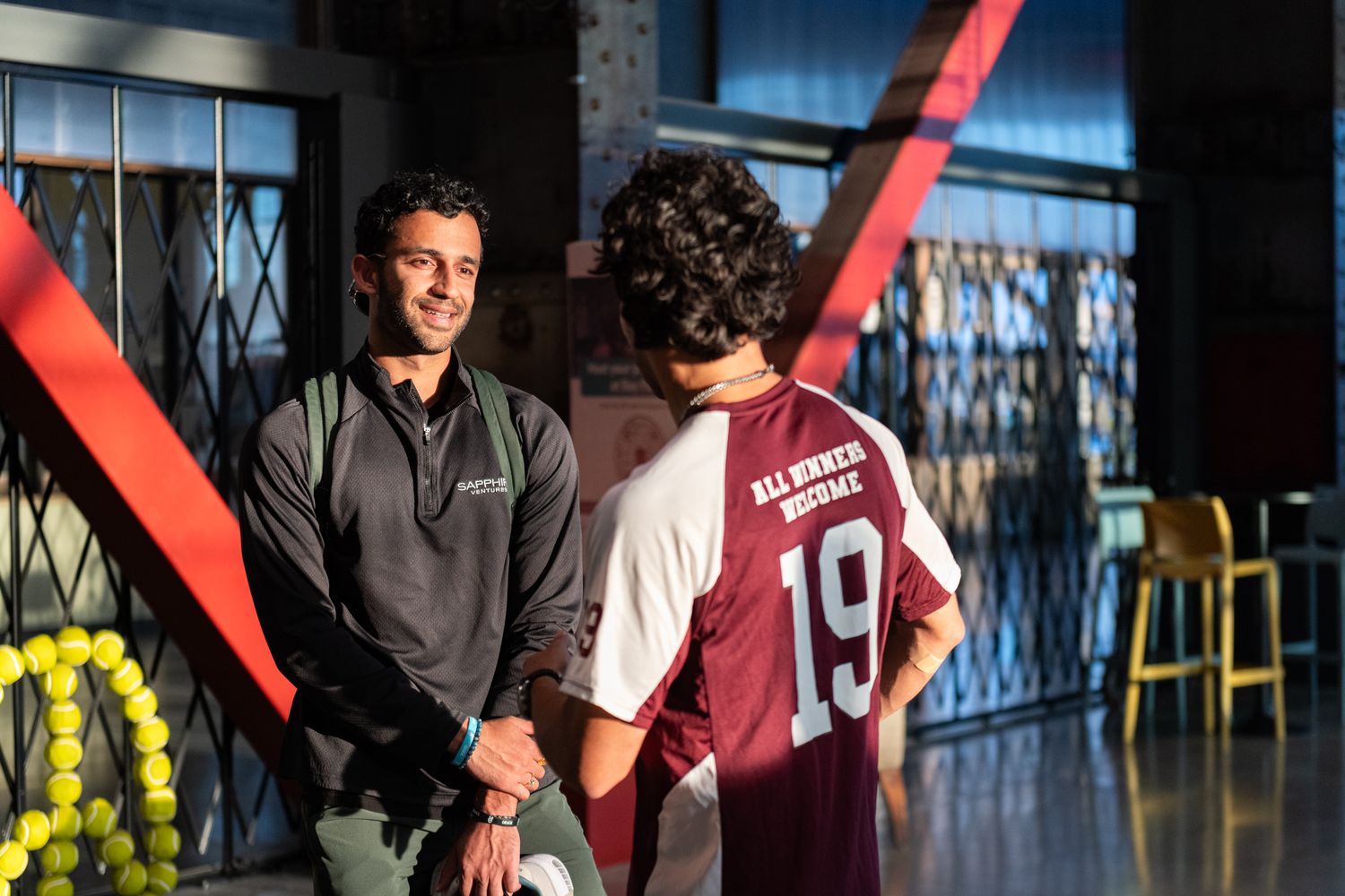 Student athletes in maroon jerseys celebrate with teammates during a sports event at an indoor venue.