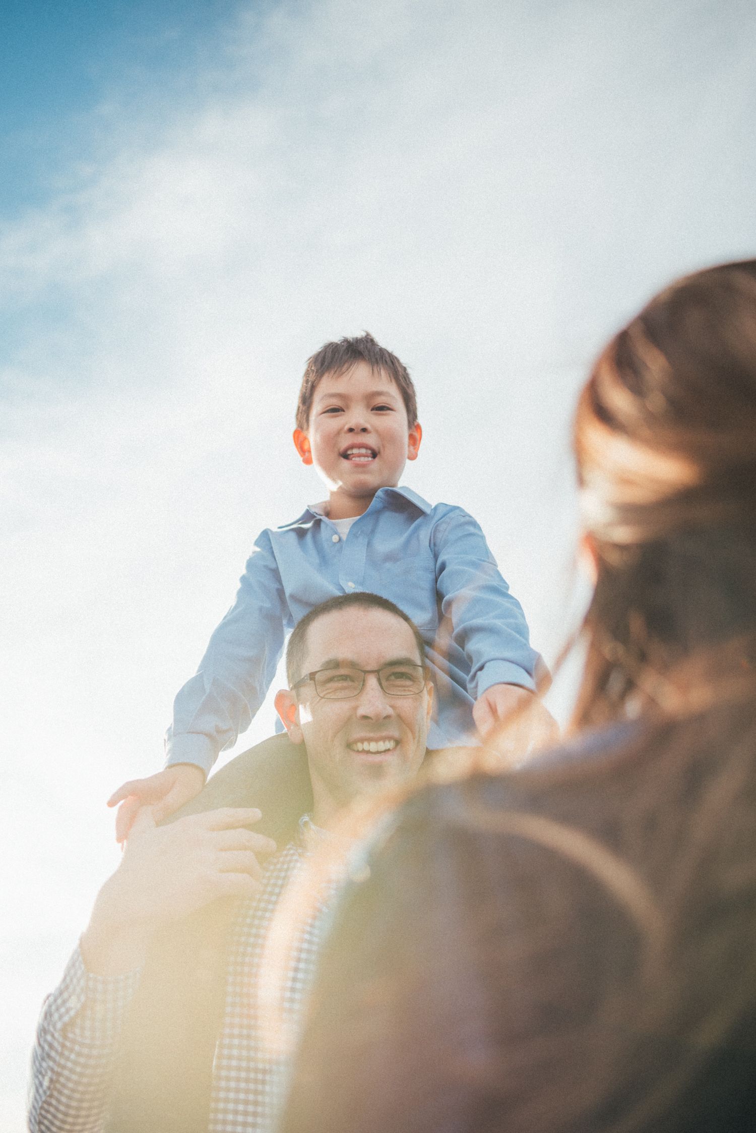Family sharing joyful moments together against bright blue sky background.