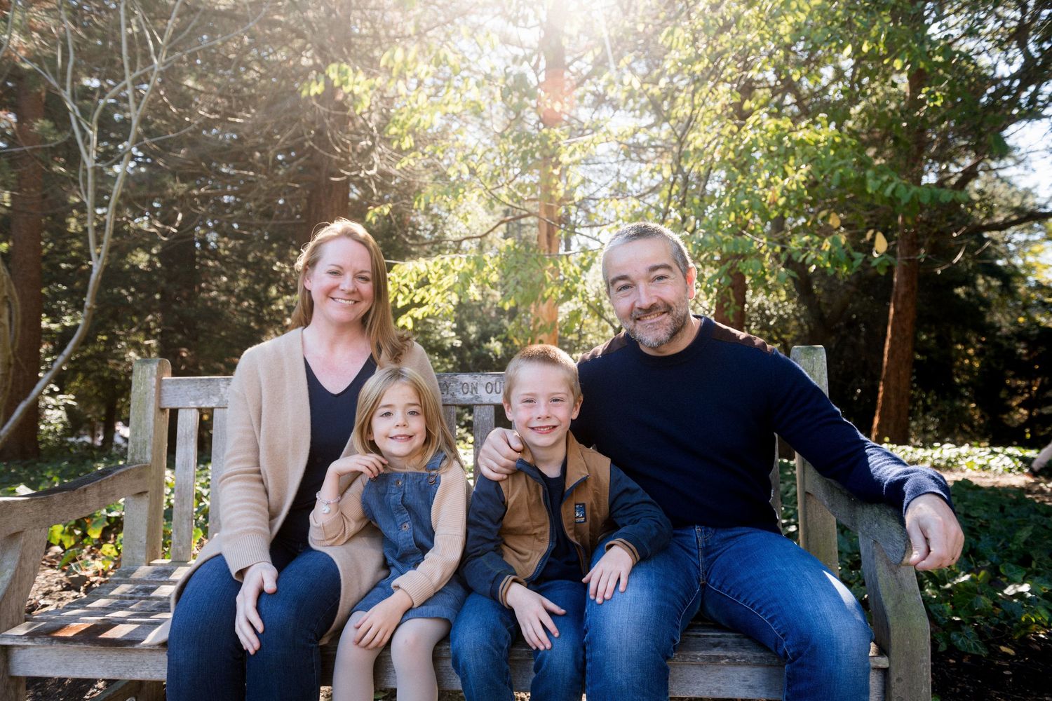 Casual family portrait session outdoors with natural lighting and greenery.