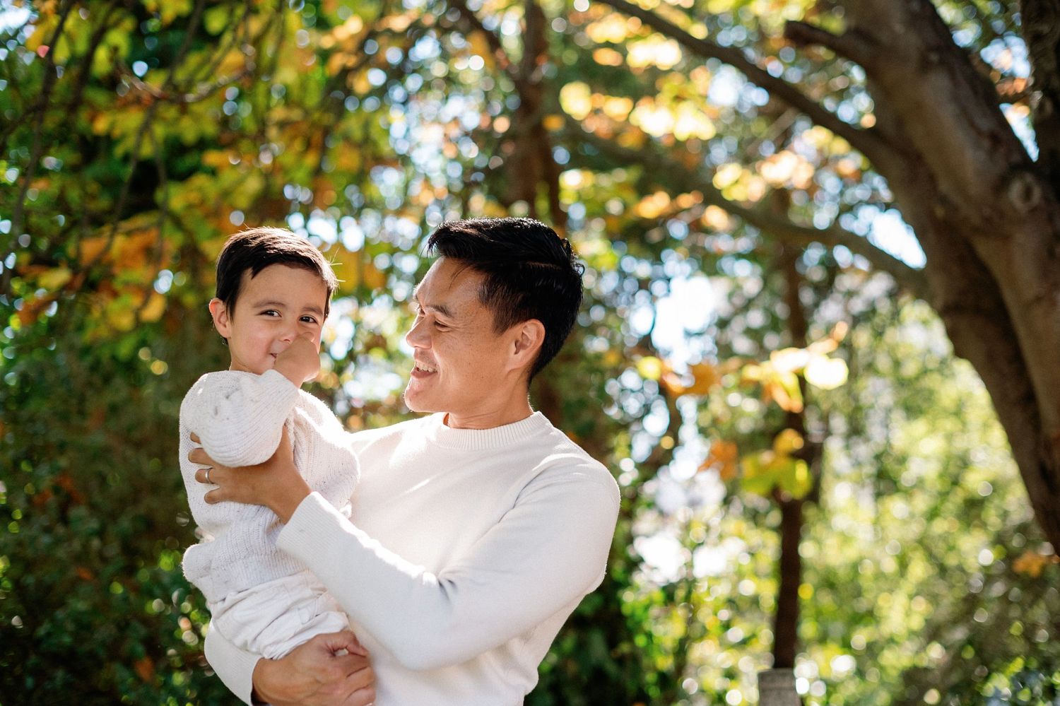Candid family interaction captured in natural sunlit garden setting.