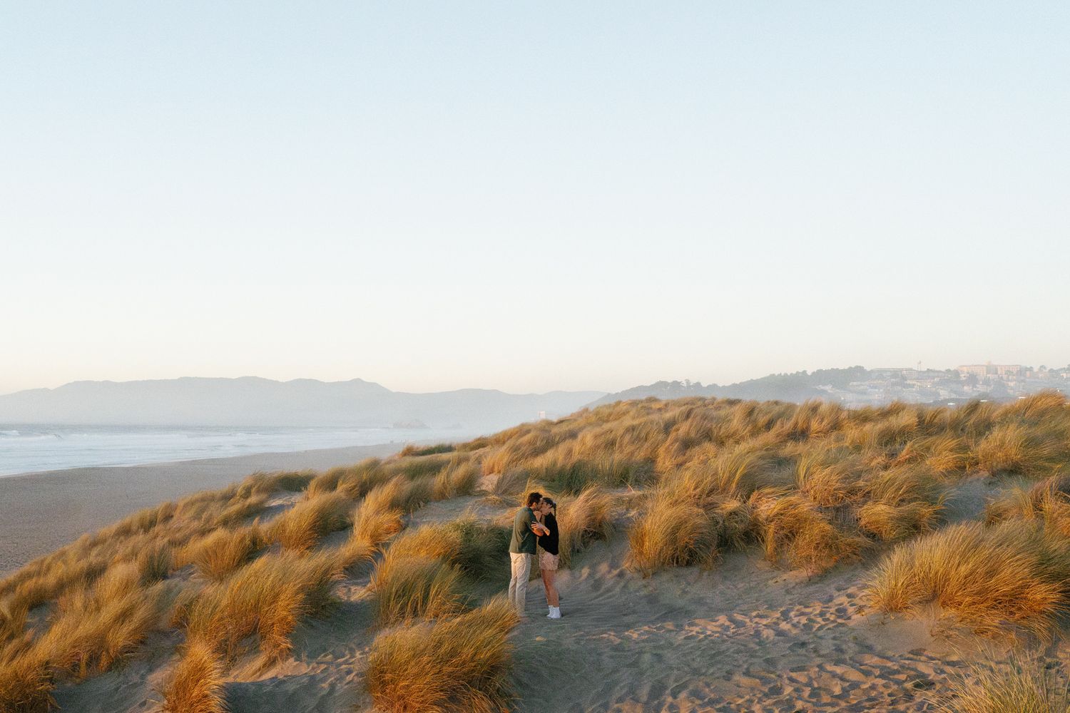 Scenic coastal landscape with golden beach grass and ocean views at sunset.