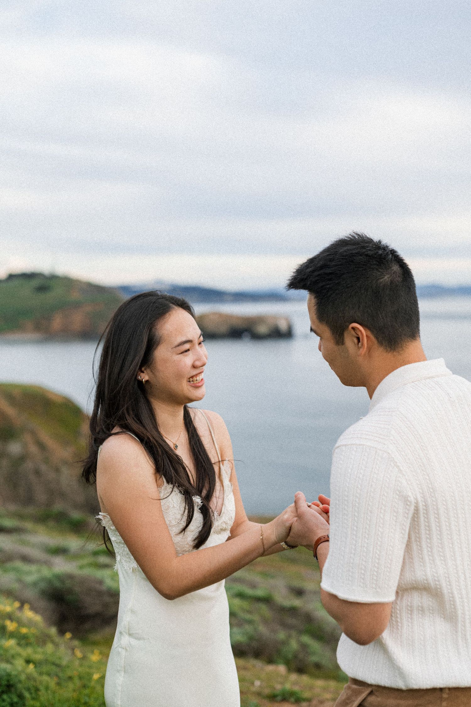 A couple shares a romantic moment during their coastal engagement photoshoot overlooking the ocean and cliffs.