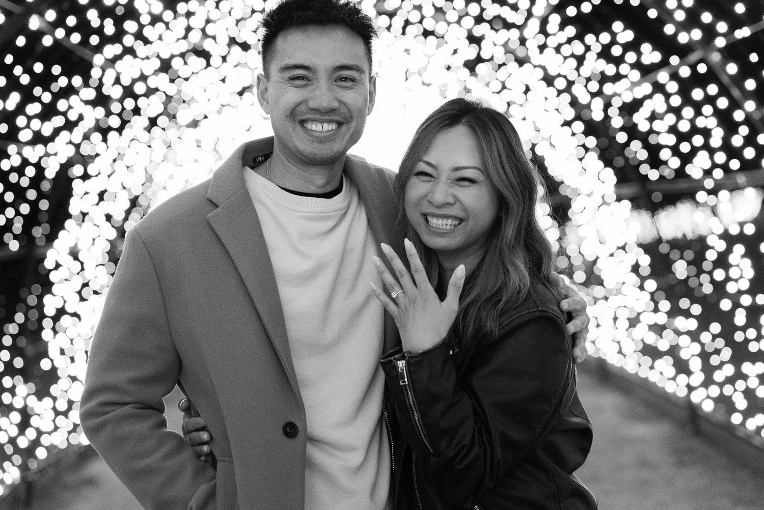 A couple shares a romantic moment under twinkling lights at an outdoor venue during an evening celebration.