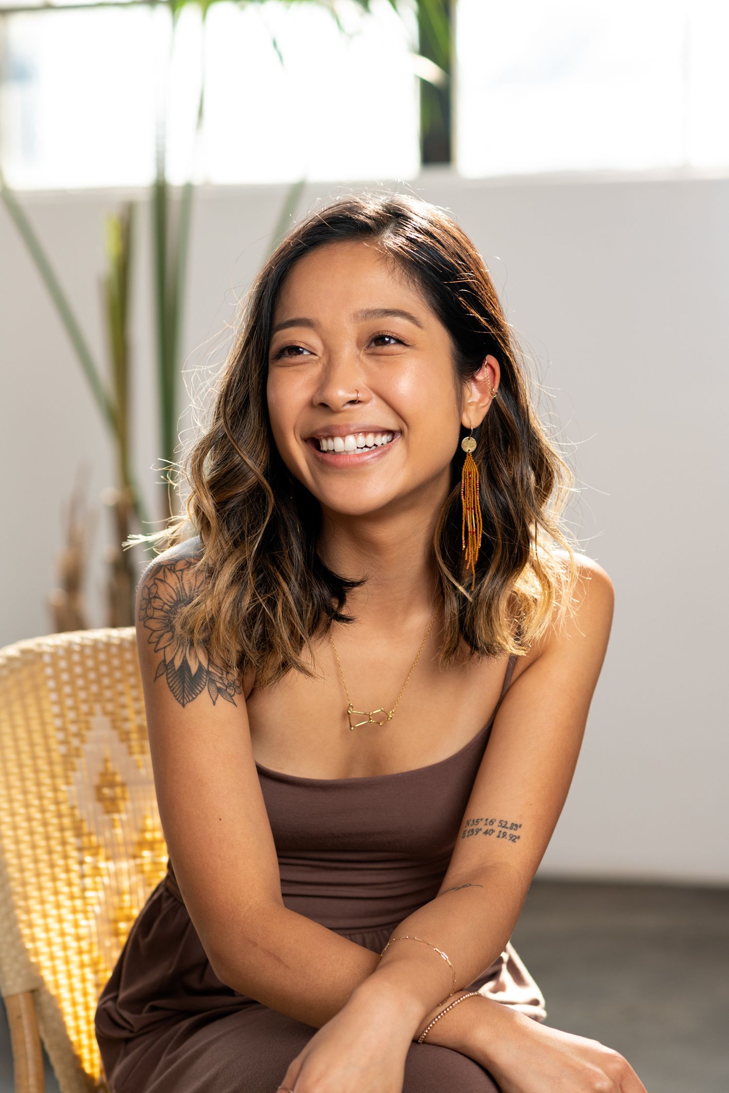 Lifestyle portraits in brown top with warm lighting and indoor plants.