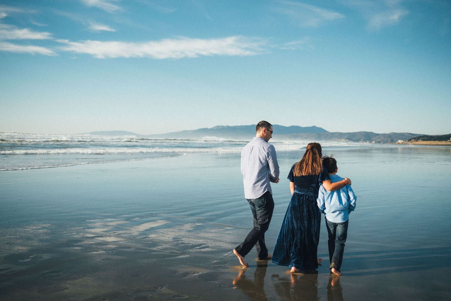 Family walking together along Ocean Beach with clear blue sky at sunset. San Francisco family photography.