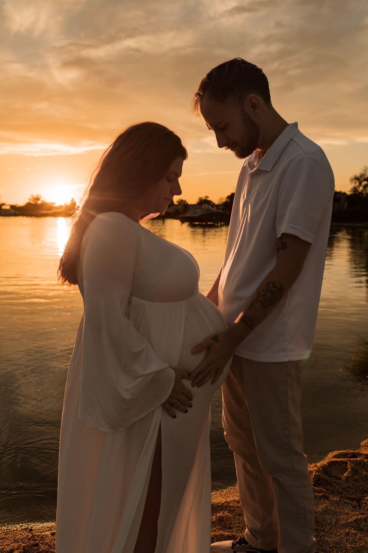 Couple embracing during a romantic outdoor maternity photography session at sunset in Maryland.