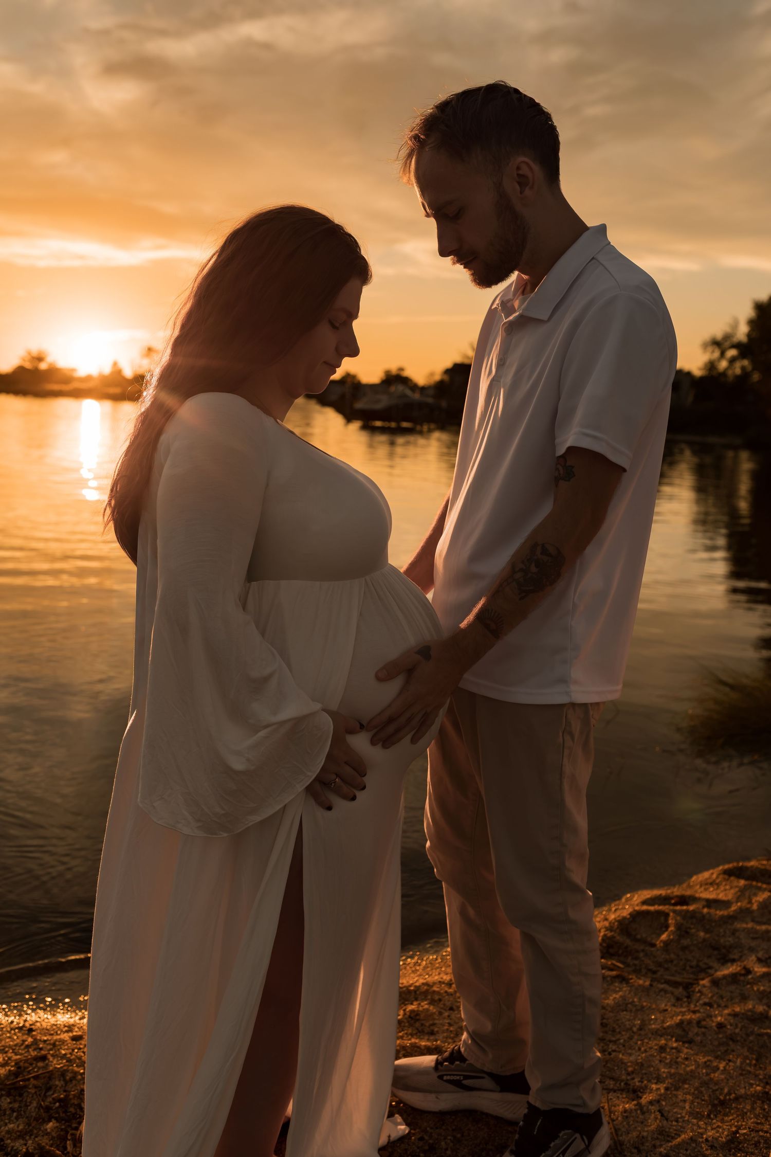 Couple embracing during a romantic outdoor maternity photography session at sunset in Maryland.