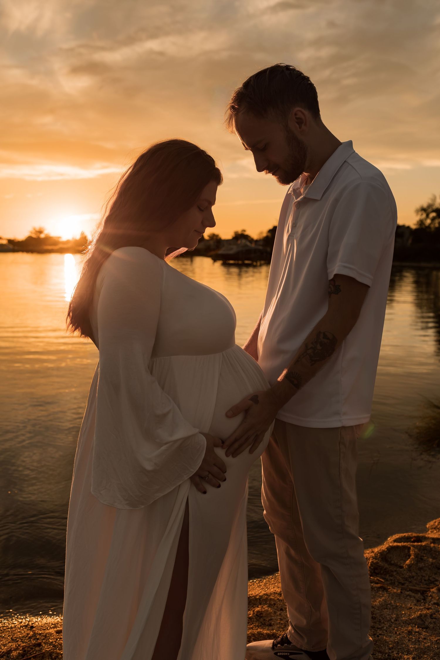 Couple embracing during a romantic outdoor maternity photography session at sunset in Maryland.