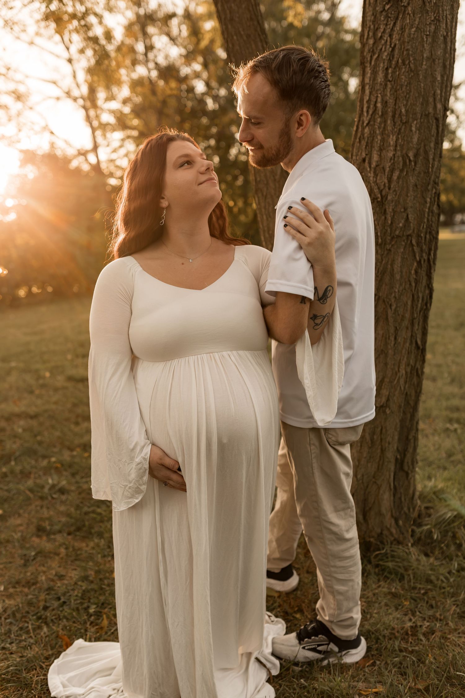 Couple embracing during a romantic outdoor maternity photography session at sunset in Maryland.