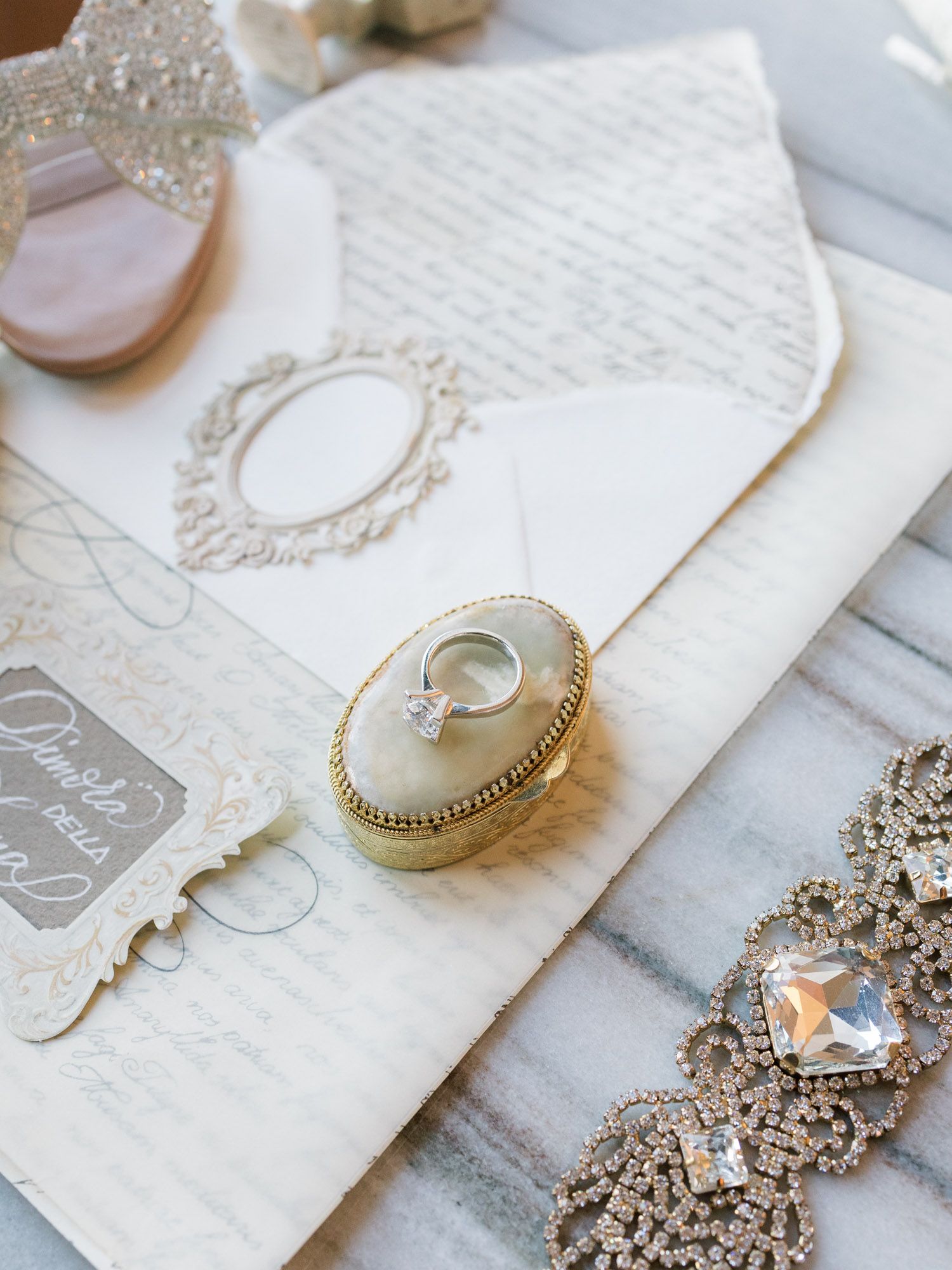 Editorial flatlay of engagement ring, invitations, and letters, wedding details photography.