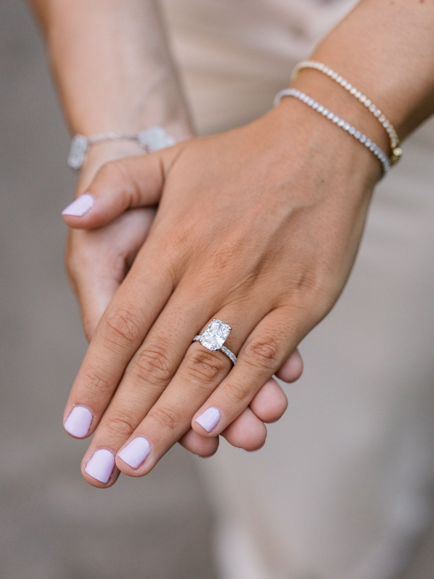 Close-up of bride’s hands displaying solitaire engagement ring, editorial proposal detail.