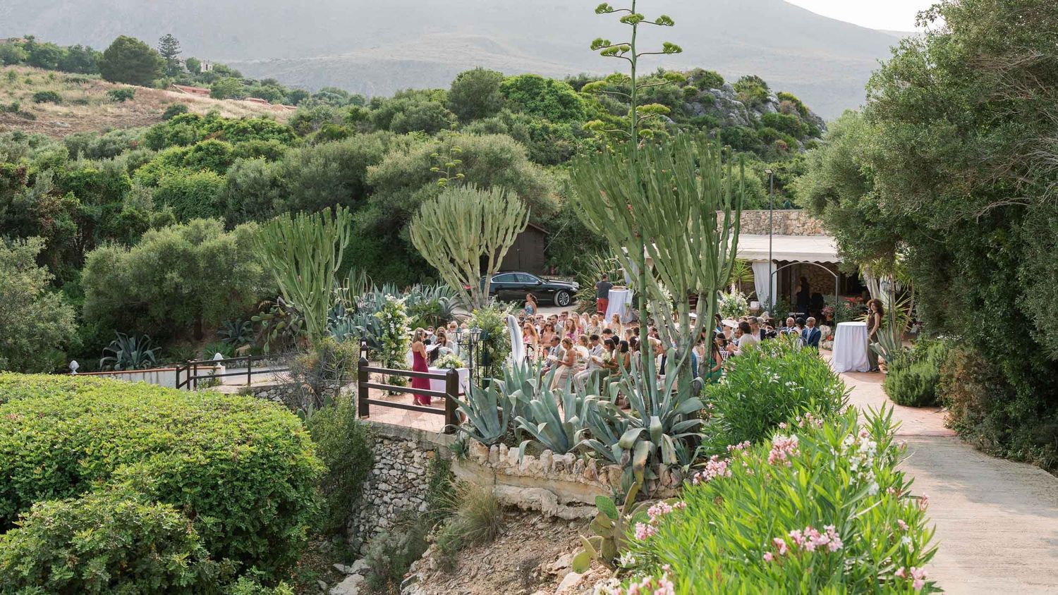 Wedding ceremony viewed from a cliff at Torre di Scopello, Sicily, luxury editorial destination.