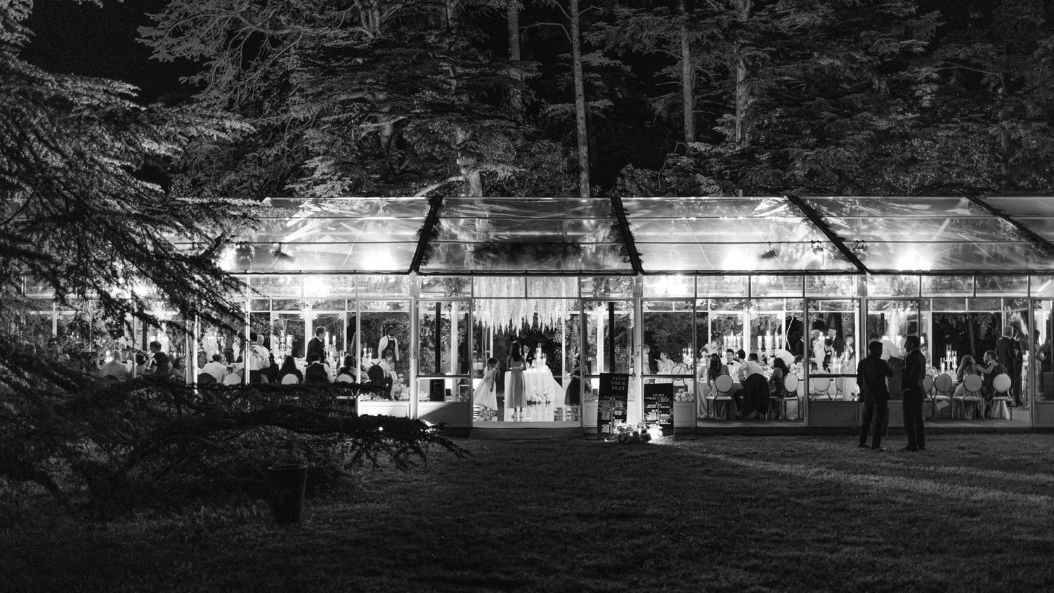 Glass venue at Isola del Garda at night, guests celebrating during wedding reception.