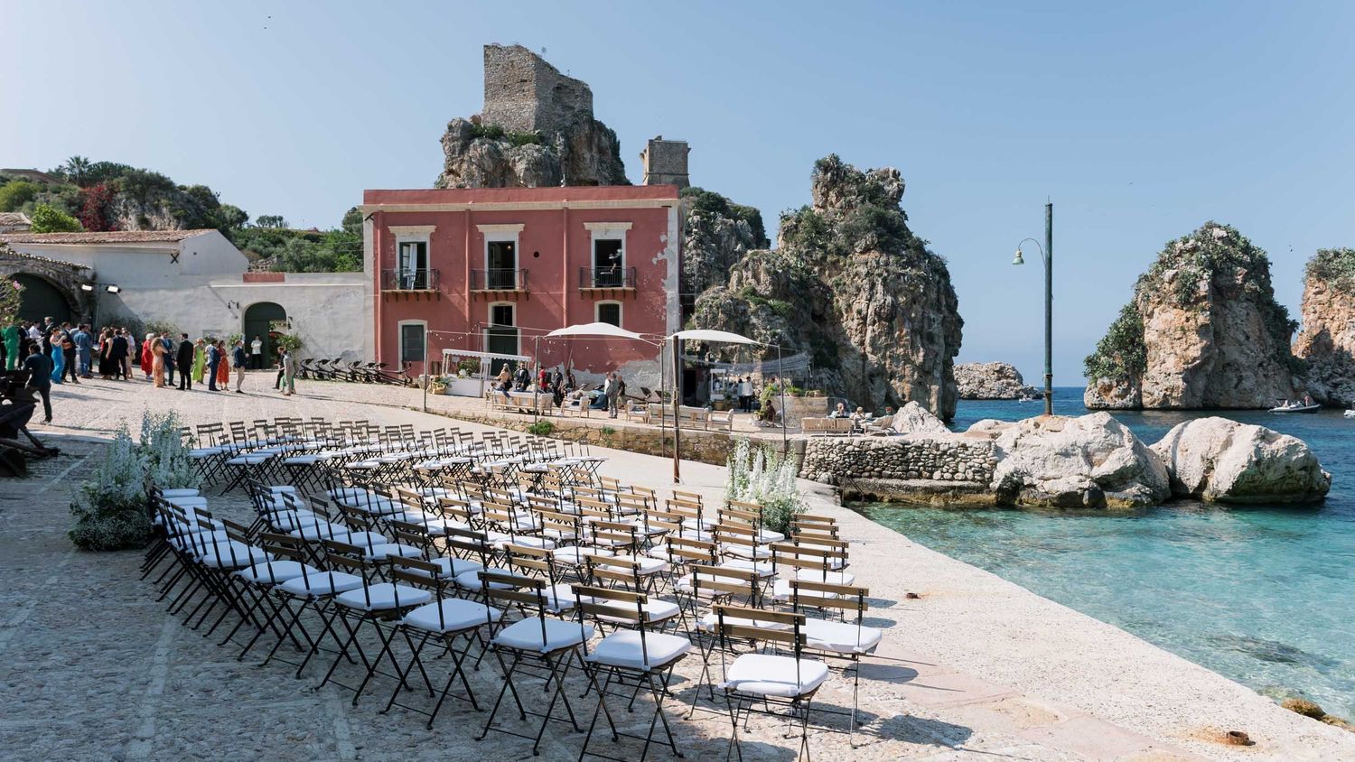 Wedding ceremony setup by the sea at Tonnara di Scopello, Sicily, luxury destination inspiration.