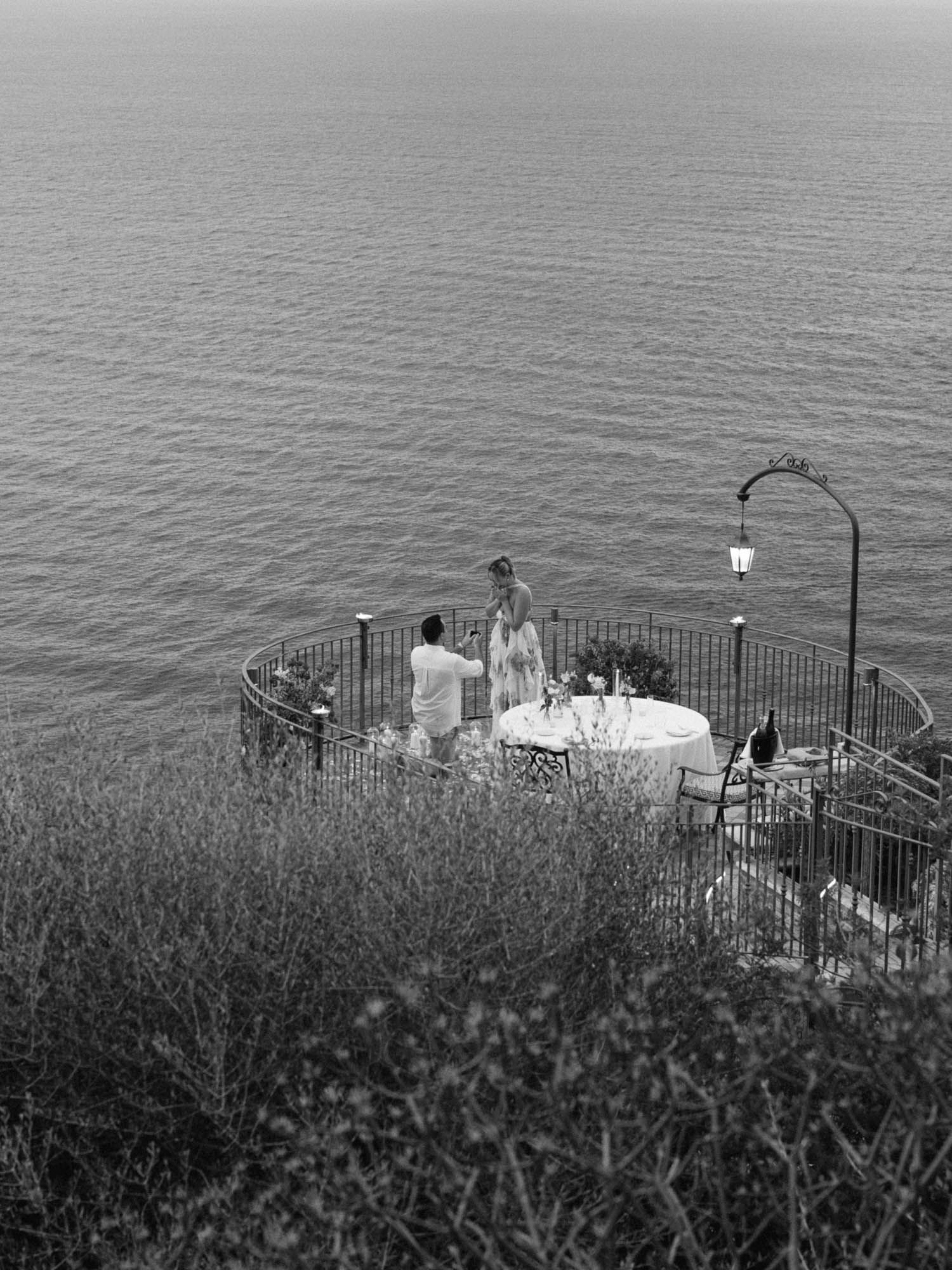 Romantic marriage proposal at Hotel San Pietro in Taormina, Sicily, groom kneeling on a panoramic balcony during a destination engagement.