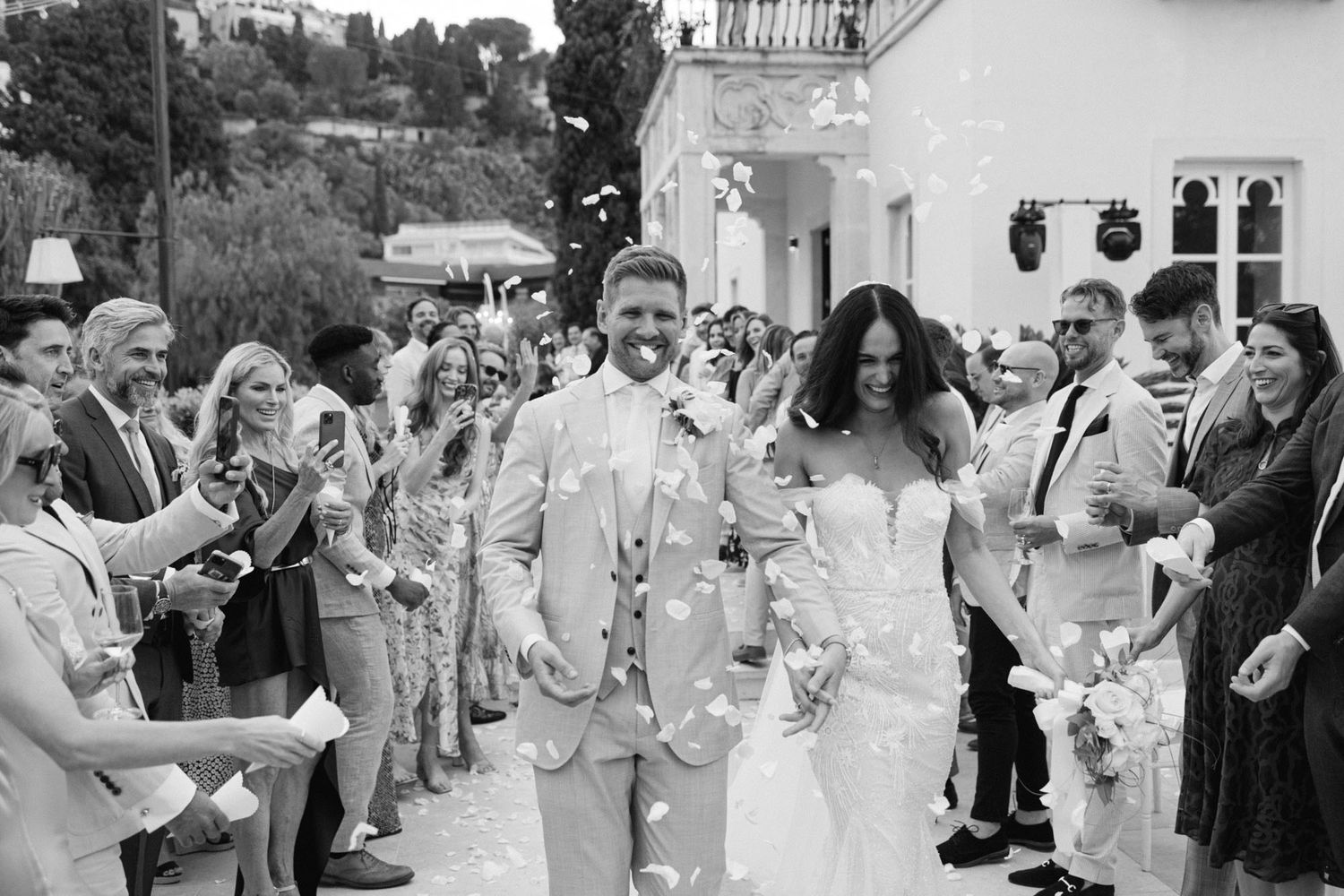 Bride and groom exiting ceremony while guests throw petals at Villa Mon Repos, Sicily, luxury wedding moment.