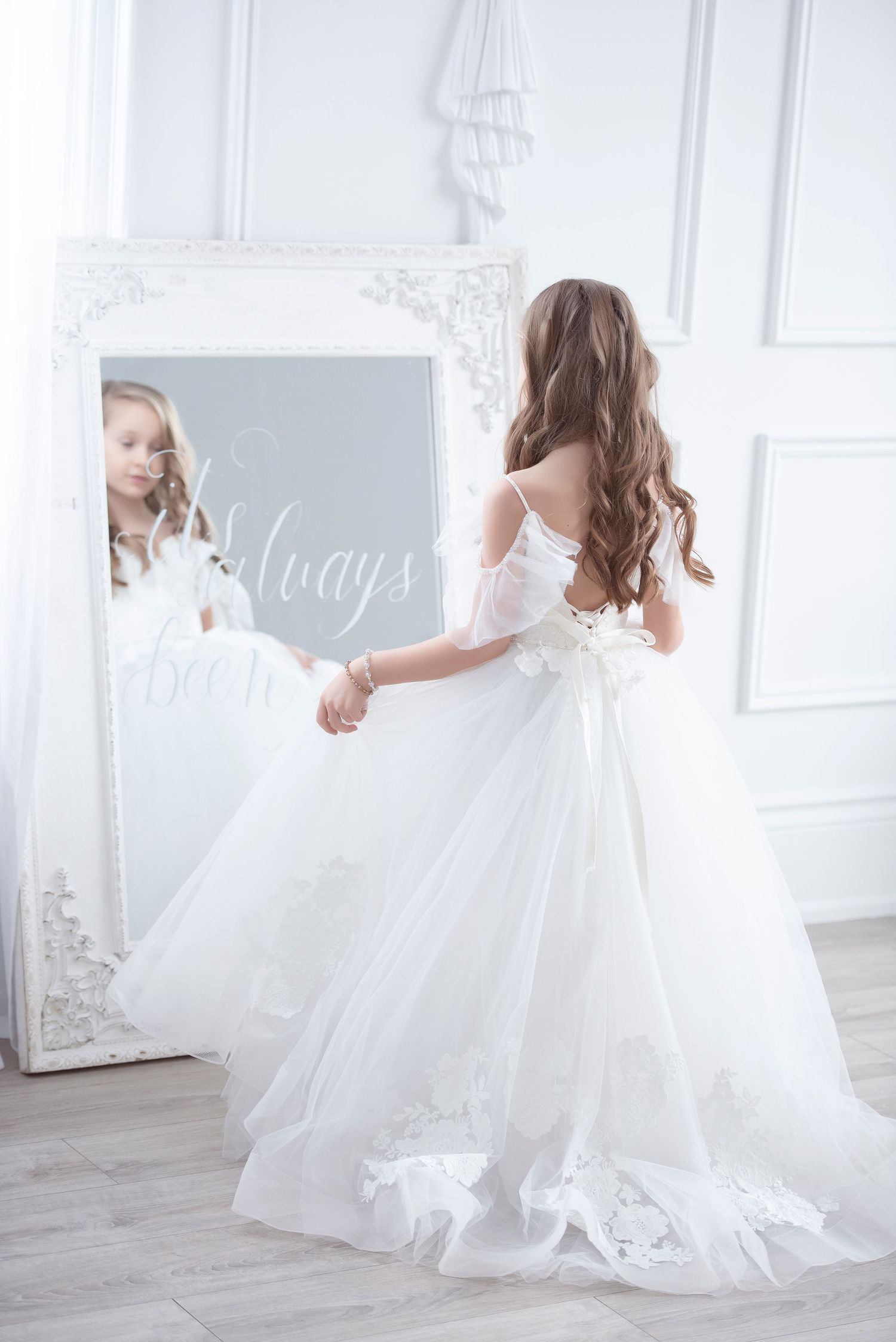 A young girl in a white ball gown admires her reflection in an ornate floor mirror. Individual photography Cambridge