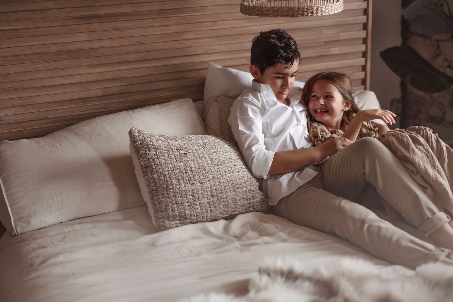 Happy couple lying on bed sharing a joyful moment in a warm, naturally lit bedroom.