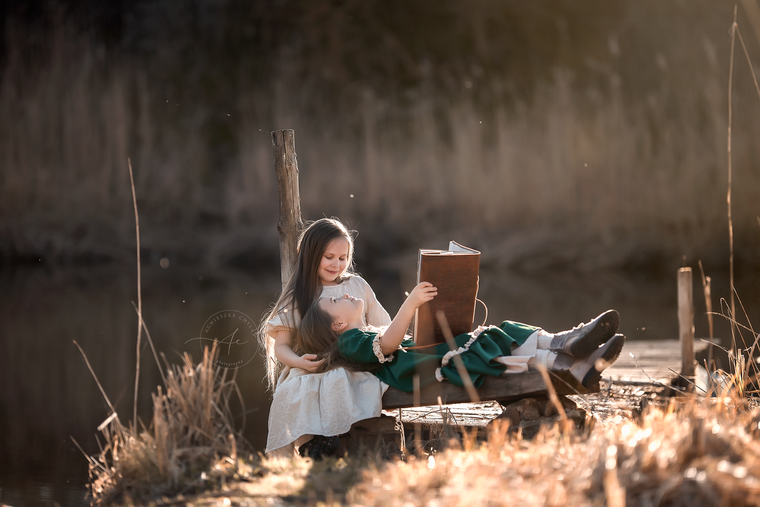Young girl reading a book on a wooden dock by a sunlit lake in a dreamy outdoor scene. Outdoor photography Burlington