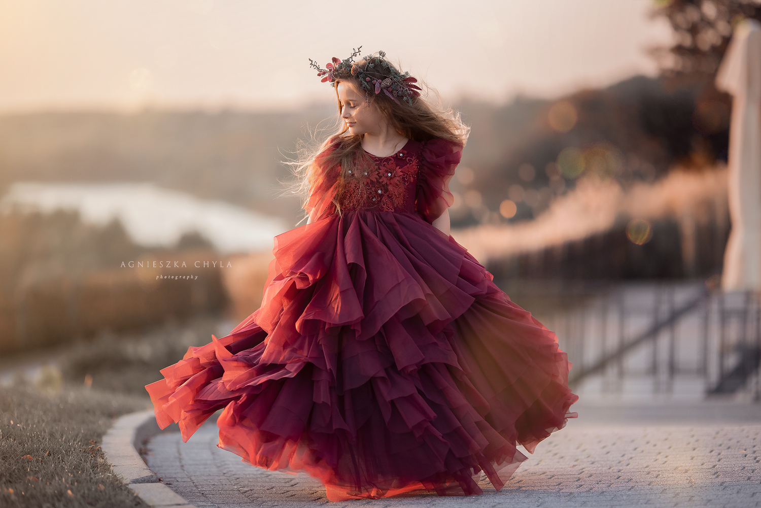 A young girl twirls in a stunning layered burgundy gown with a floral crown at sunset. Headshots and portraits photography Oakville