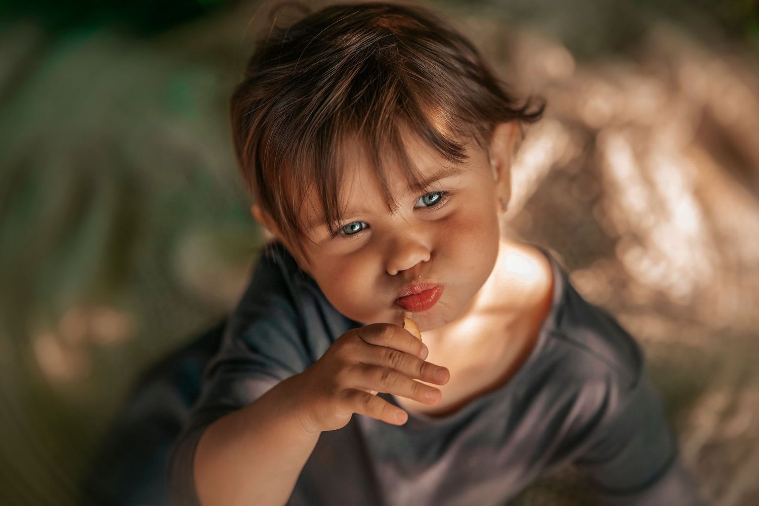 Adorable toddler with brown hair gazing up at camera with a curious expression in warm natural light.
