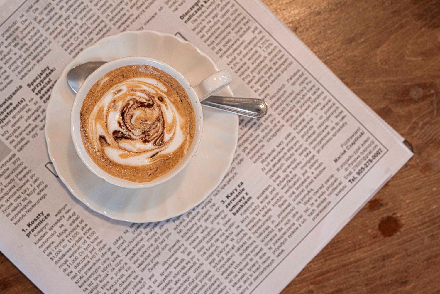 A beautifully crafted rose latte art cappuccino in a white cup placed on an open newspaper. Commercial photography
Toronto