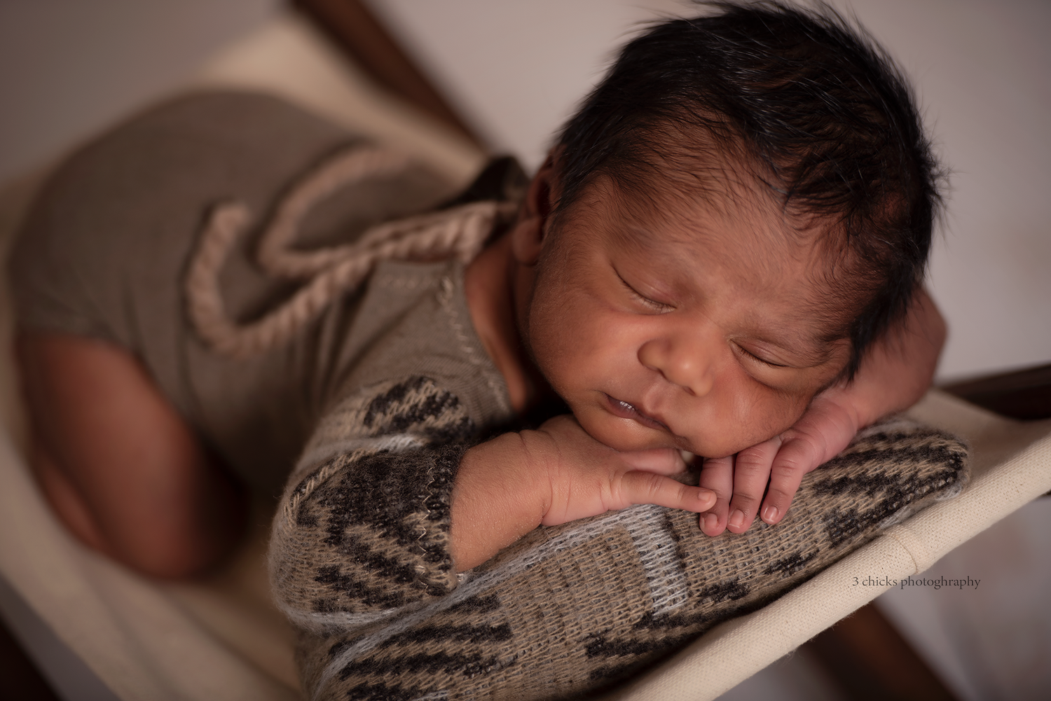 Peaceful newborn baby sleeping in a small wooden bed, wrapped in a cozy knit outfit, with tiny hands tucked under chin.