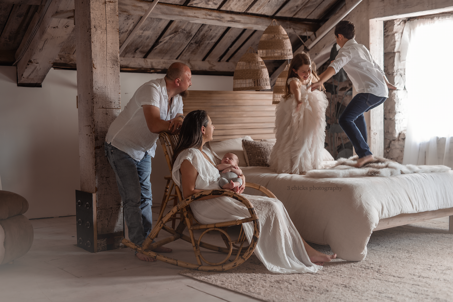 Family with newborn baby enjoys a relaxed moment in a rustic wooden bedroom interior.