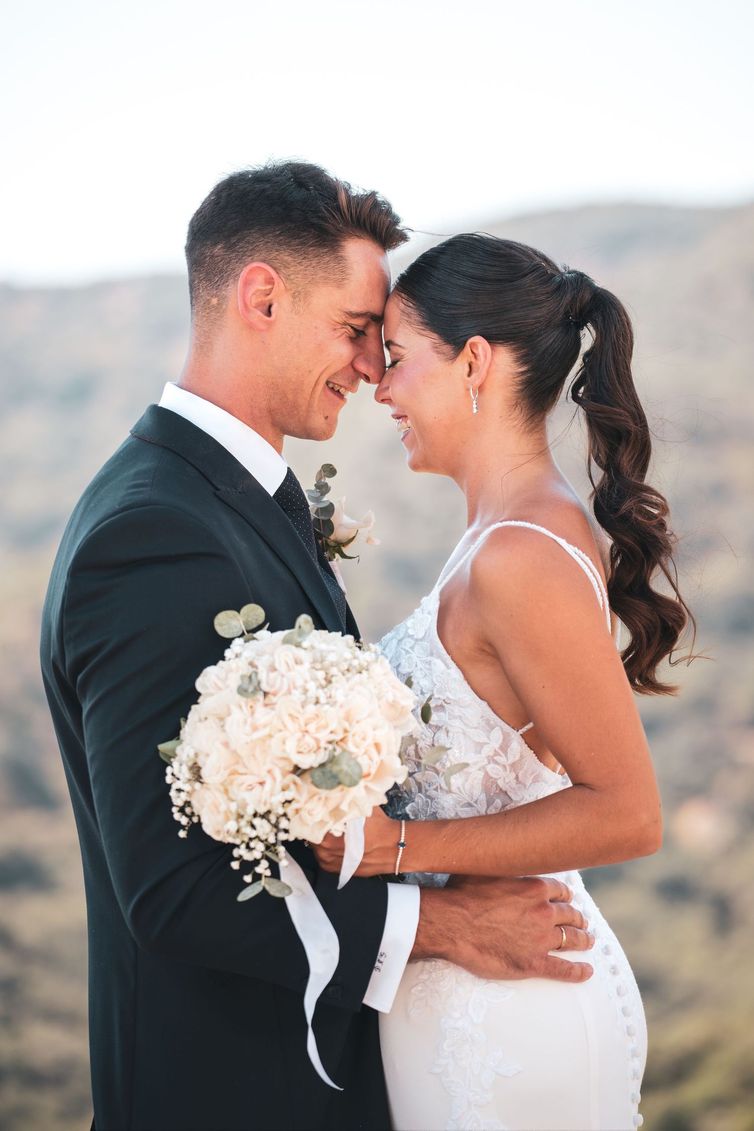 Retrato posado de una pareja de novios en exteriores, con un paisaje de montaña de fondo. Sesión de fotos de boda en Andalucía.