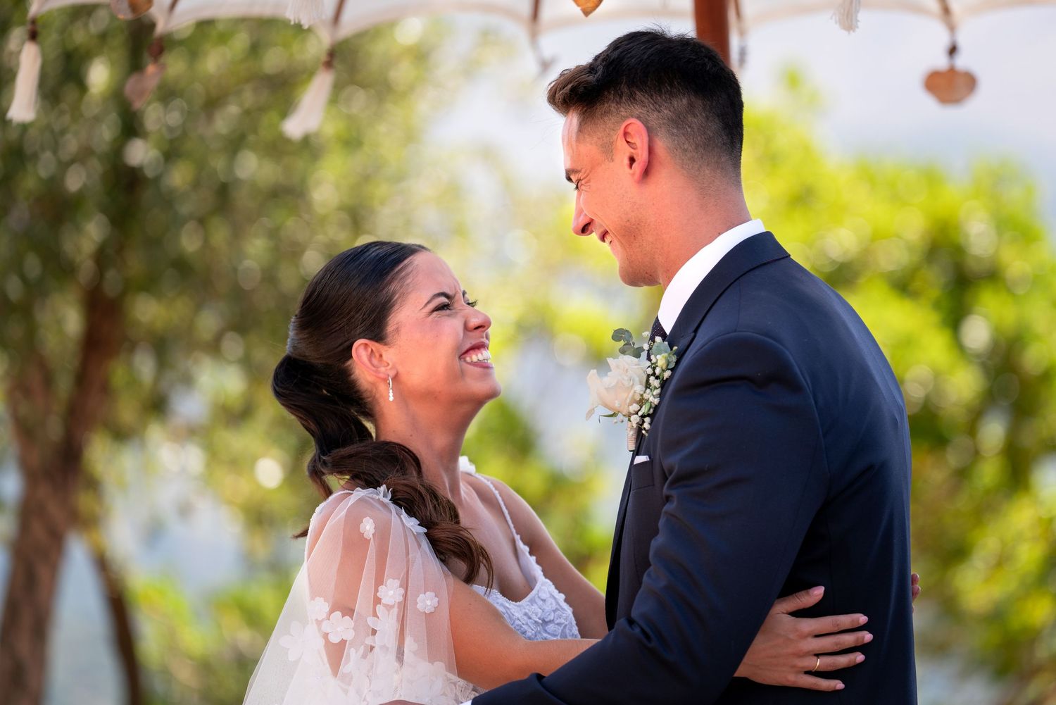 Novios riendo a carcajadas y mirándose a los ojos durante su boda al aire libre. Fotografía de boda espontánea, natural y feliz en Málaga.